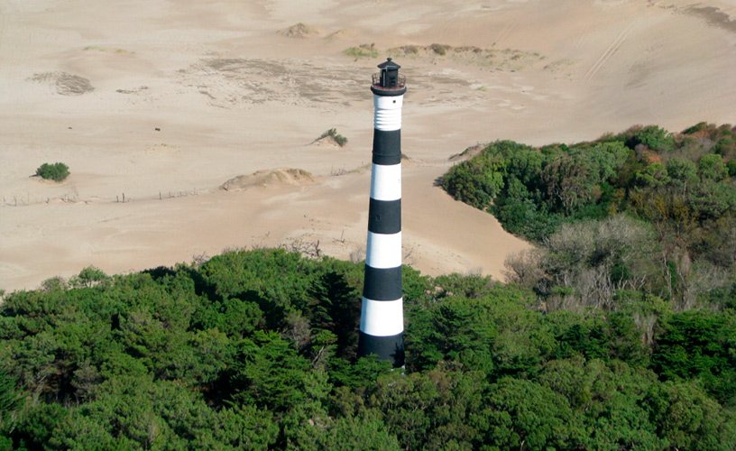 Faro Querandí, blanco y negro, entre médanos y bosque