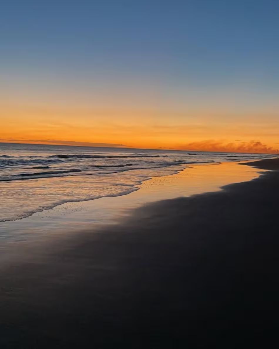 Orilla del mar al atardecer con cielo naranja